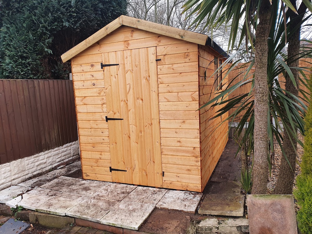 New timber apex shed on a paved base with fencing behind