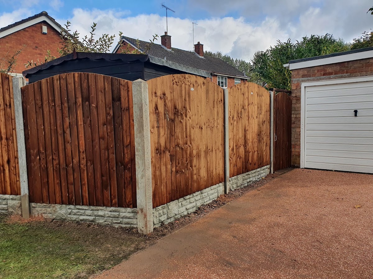 Arched-top closeboard fence panels on concrete posts and gravel boards, fitted beside a garage