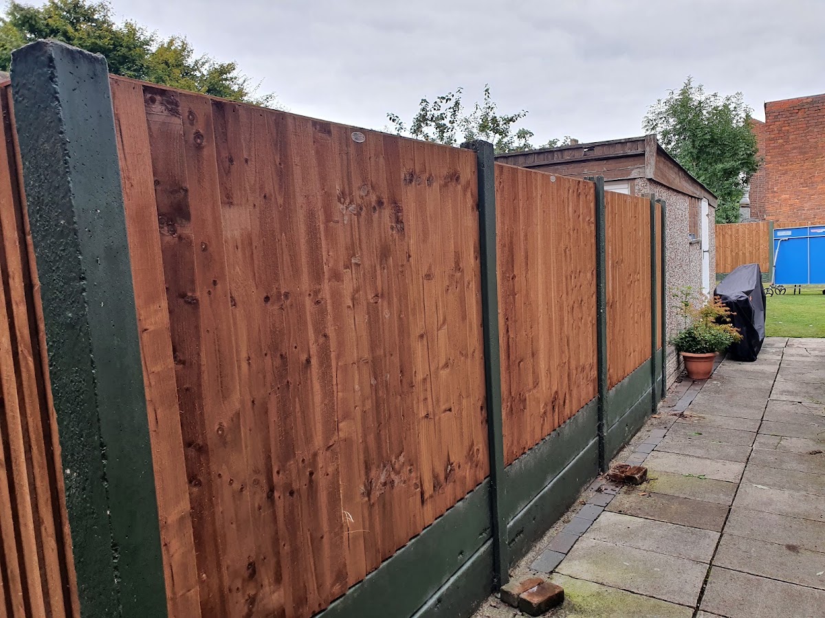 Feather-edge closeboard fencing on green concrete posts and gravel boards along a garden path